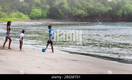 Kinder spielen zusammen an einem tropischen Strand mit einem Wald im Hintergrund. Playas del Coco, Guanacaste, Costa Rica. Stockfoto