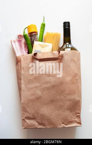 Papiertüte mit Lebensmittelvorräte, Krisenlebensmittelvorrat für Quarantäneisolation,. Salat, Pasta, Butter, Wein, Chili, Speck. Lieferung von Lebensmitteln, Spende Stockfoto