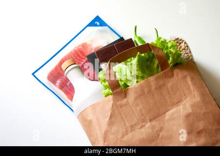 Papiertüte mit Lebensmittelvorräte, Krisenlebensmittelvorrat für Quarantäneisolation Periode.Salat, Öl, Schokolade, Speck, Linsen. Spende für die Lieferung von Lebensmitteln Stockfoto