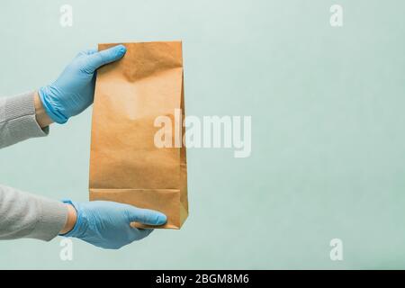 Lieferung Frau hält Handwerk Papiertasche in medizinischen Gummihandschuhe. Copy space. Schnelle und kostenlose Lieferung . Online-Shopping. Quarantäne Stockfoto