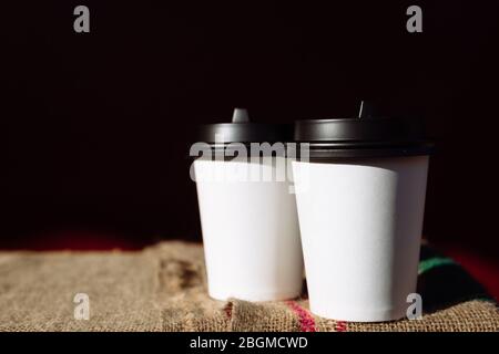 Zwei Kaffeetassen aus Papier zerstoßen auf der Lache. Tasse Kaffeebohnen zum Mitnehmen Stockfoto