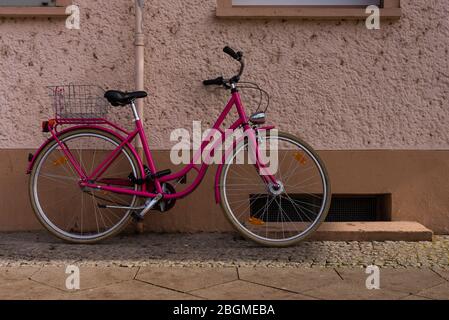 Ein pinkfarbenes Fahrrad, das auf einer Hauswand steht Stockfoto
