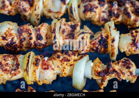 Leckere geröstete Grill Nahaufnahme. Hausgemachte Hühnchen-Schisch-Kabobs mit gebackenen Zwiebeln. Gegrillte Hähnchenfleisch-Spieße auf dunklem Hintergrund. Stockfoto