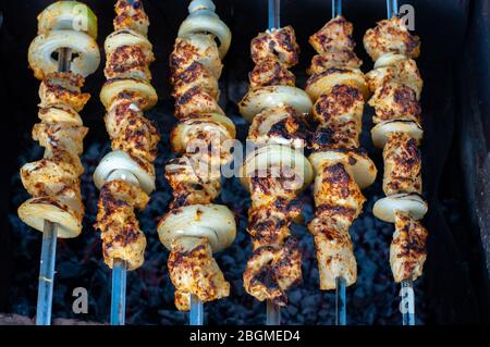 Draufsicht auf hausgemachte Hühnchen-Schisch-Kabobs mit frischen Zwiebeln. Gegrillte Hähnchenfleisch-Spieße auf dunklem Hintergrund. Leckeres Essen für Picknick. Stockfoto