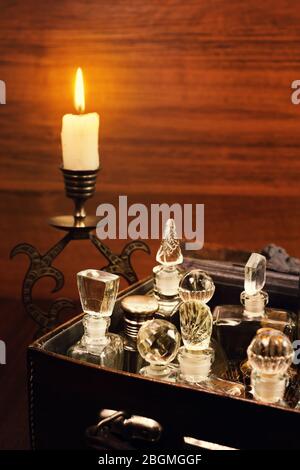 Kerzenlicht im bronse Kerzenständer und verschiedene Vintage Parfüm Flaschen im alten Leder Gripsack Stockfoto