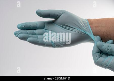 Ein Mann zieht Latexhandschuhe an, um sich vor Covid-19 zu schützen Stockfoto