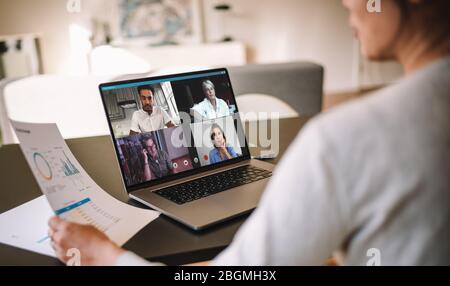 Bürokollegen, die ein Videogespräch führen, um einige Finanzberichte zu besprechen. Geschäftsleute, die von zu Hause aus arbeiten und eine Videokonferenz abhalten. Über die Schulter Stockfoto