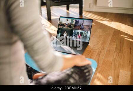 Gruppe von Personen, die Yoga mit dem Trainer über eine Videokonferenz üben. Fitness Coach unterrichtet Yoga online für Gruppe von Menschen. Stockfoto