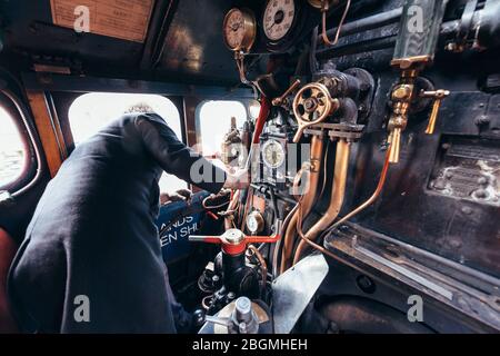 Ein Mann steuert die Zifferblätter und Hebel in der cab Working britischen Dampflokomotive, die Sir Nigel Gresley (LNER Klasse A4 Pacific 4498), in British Rail Stockfoto