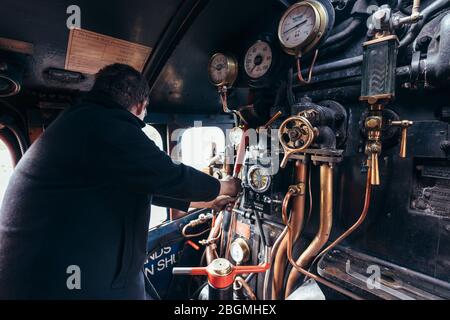 Ein Mann steuert die Zifferblätter und Hebel in der cab Working britischen Dampflokomotive, die Sir Nigel Gresley (LNER Klasse A4 Pacific 4498), in British Rail Stockfoto
