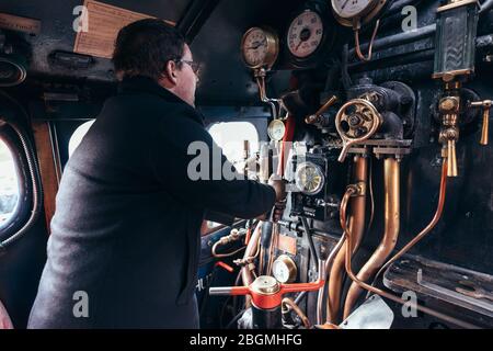 Ein Mann steuert die Zifferblätter und Hebel in der cab Working britischen Dampflokomotive, die Sir Nigel Gresley (LNER Klasse A4 Pacific 4498), in British Rail Stockfoto