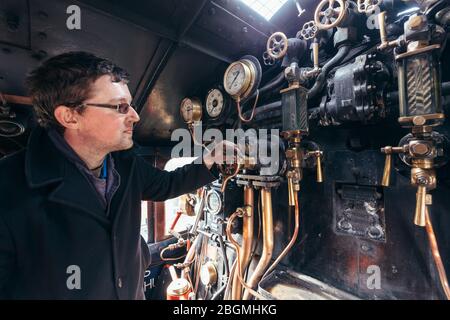 Ein Mann steuert die Zifferblätter und Hebel in der cab Working britischen Dampflokomotive, die Sir Nigel Gresley (LNER Klasse A4 Pacific 4498), in British Rail Stockfoto