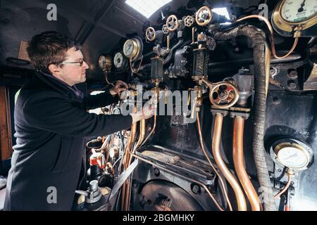 Ein Mann steuert die Zifferblätter und Hebel in der cab Working britischen Dampflokomotive, die Sir Nigel Gresley (LNER Klasse A4 Pacific 4498), in British Rail Stockfoto