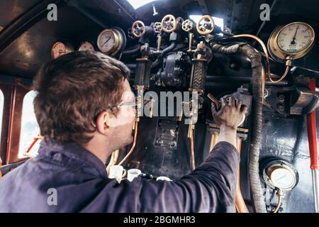 Ein Mann steuert die Zifferblätter und Hebel in der cab Working britischen Dampflokomotive, die Sir Nigel Gresley (LNER Klasse A4 Pacific 4498), in British Rail Stockfoto