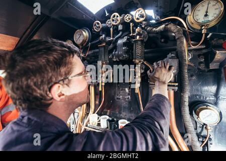Ein Mann steuert die Zifferblätter und Hebel in der cab Working britischen Dampflokomotive, die Sir Nigel Gresley (LNER Klasse A4 Pacific 4498), in British Rail Stockfoto