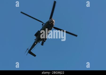 Das Untergestell eines Militärhubschraubers erfasste das Fliegen über dem Kopf in niedriger Höhe Stockfoto