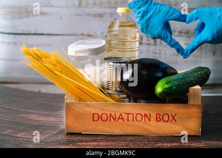 Lebensmittel. Krise Lebensmittel Box Lager für Coronavirus Quarantäne Isolationszeit in Holz Hintergrund. Verschiedene Lebensmittel in Aluminiumdosen, Reis, Nudeln, Öl Stockfoto