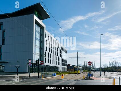 Metrolink Tram vorbei am Holiday Inn Express am Eröffnungstag der Trafford Park Line, 22. März 2020. Barton Dock Rd., Trafford, Manchester, Großbritannien Stockfoto
