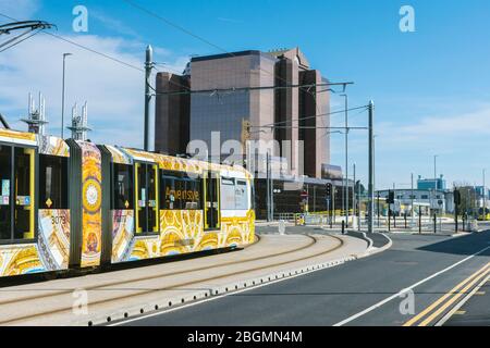 Metrolink Straßenbahn nähert sich dem Quay West Gebäude am Eröffnungstag der Trafford Park Linie. Trafford Wharf Rd., Trafford, Manchester, Großbritannien Stockfoto