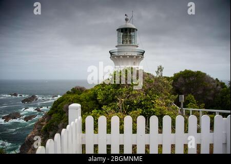 Sugarloaf Point Lighthouse bei Seal Rocks, Myall Lakes National Park, NSW, Australien. Leuchtturm auf Hügel, raue See und graue Wolke Himmel Stockfoto