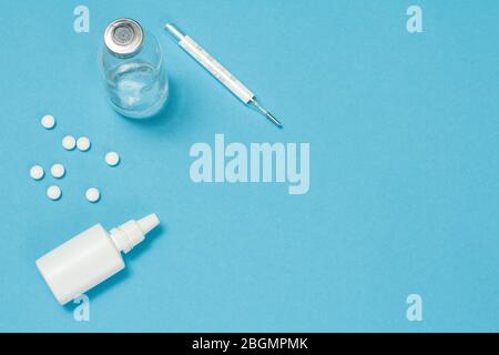 Nasenspray, Pillen, eine Glasflasche und ein Quecksilberthermometer. Draufsicht. Konzept des Behandlungskits. Stockfoto