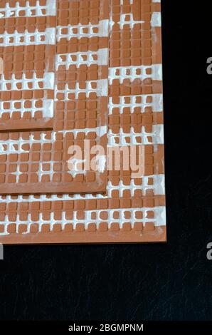 Keramikfliesen Rückseite. Drei Keramikfliesen auf schwarzem Hintergrund. Die Rückseite der keramischen Wandfliesen. Baumaterialien. Selektiver Fokus. Stockfoto