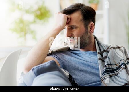 Mann, der sich unwohl fühlt, während er zu Hause sitzt Stockfoto