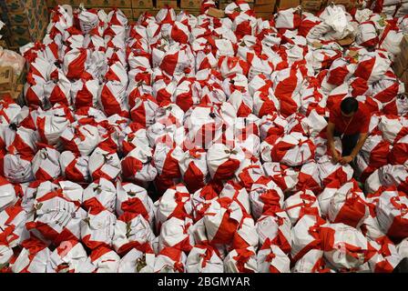 Jakarta, Jakarta, Indonesien. April 2020. Arbeiter packen Sozialhilfepakete (Sozialhilfe) im Cipinang Food Station Warehouse, Jakarta, 22. April 2020. Die Regierung verteilte Sozialhilfepakete für drei Monate, um die Bewohner davon abzuhalten, nach Hause zu gehen, und um während der COVID-19-Pandemie die Kaufkraft für bedürftige Bewohner im Großraum Jakarta zu erhöhen. Kredit: Dasril Roszandi/ZUMA Wire/Alamy Live News Stockfoto