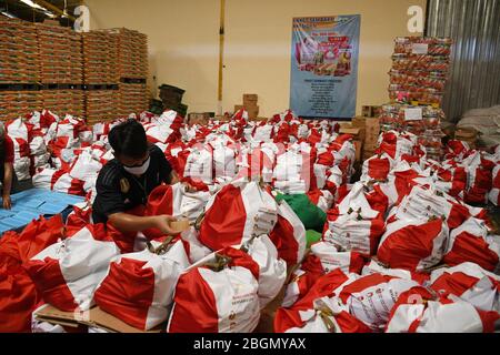 Jakarta, Jakarta, Indonesien. April 2020. Arbeiter packen Sozialhilfepakete (Sozialhilfe) im Cipinang Food Station Warehouse, Jakarta, 22. April 2020. Die Regierung verteilte Sozialhilfepakete für drei Monate, um die Bewohner davon abzuhalten, nach Hause zu gehen, und um während der COVID-19-Pandemie die Kaufkraft für bedürftige Bewohner im Großraum Jakarta zu erhöhen. Kredit: Dasril Roszandi/ZUMA Wire/Alamy Live News Stockfoto