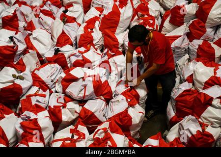 Jakarta, Jakarta, Indonesien. April 2020. Arbeiter packen Sozialhilfepakete (Sozialhilfe) im Cipinang Food Station Warehouse, Jakarta, 22. April 2020. Die Regierung verteilte Sozialhilfepakete für drei Monate, um die Bewohner davon abzuhalten, nach Hause zu gehen, und um während der COVID-19-Pandemie die Kaufkraft für bedürftige Bewohner im Großraum Jakarta zu erhöhen. Kredit: Dasril Roszandi/ZUMA Wire/Alamy Live News Stockfoto