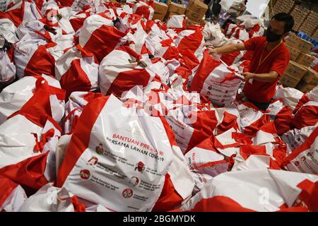 Jakarta, Jakarta, Indonesien. April 2020. Arbeiter packen Sozialhilfepakete (Sozialhilfe) im Cipinang Food Station Warehouse, Jakarta, 22. April 2020. Die Regierung verteilte Sozialhilfepakete für drei Monate, um die Bewohner davon abzuhalten, nach Hause zu gehen, und um während der COVID-19-Pandemie die Kaufkraft für bedürftige Bewohner im Großraum Jakarta zu erhöhen. Kredit: Dasril Roszandi/ZUMA Wire/Alamy Live News Stockfoto