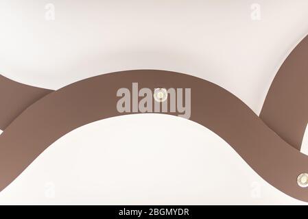 Stretch-Decke in hellbrauner Farbe mit Lampen. Stockfoto