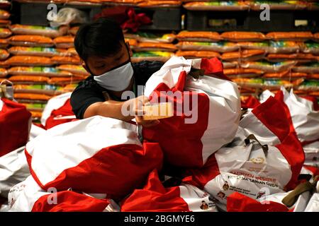 Jakarta, Jakarta, Indonesien. April 2020. Arbeiter packen Sozialhilfepakete (Sozialhilfe) im Cipinang Food Station Warehouse, Jakarta, 22. April 2020. Die Regierung verteilte Sozialhilfepakete für drei Monate, um die Bewohner davon abzuhalten, nach Hause zu gehen, und um während der COVID-19-Pandemie die Kaufkraft für bedürftige Bewohner im Großraum Jakarta zu erhöhen. Kredit: Dasril Roszandi/ZUMA Wire/Alamy Live News Stockfoto