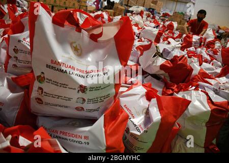 Jakarta, Jakarta, Indonesien. April 2020. Arbeiter packen Sozialhilfepakete (Sozialhilfe) im Cipinang Food Station Warehouse, Jakarta, 22. April 2020. Die Regierung verteilte Sozialhilfepakete für drei Monate, um die Bewohner davon abzuhalten, nach Hause zu gehen, und um während der COVID-19-Pandemie die Kaufkraft für bedürftige Bewohner im Großraum Jakarta zu erhöhen. Kredit: Dasril Roszandi/ZUMA Wire/Alamy Live News Stockfoto