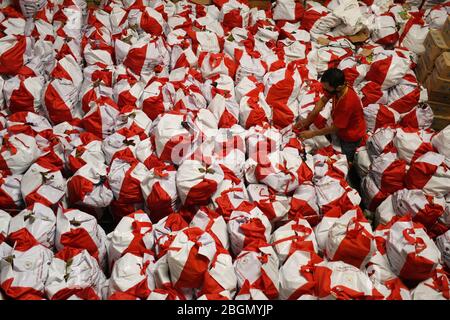 Jakarta, Jakarta, Indonesien. April 2020. Arbeiter packen Sozialhilfepakete (Sozialhilfe) im Cipinang Food Station Warehouse, Jakarta, 22. April 2020. Die Regierung verteilte Sozialhilfepakete für drei Monate, um die Bewohner davon abzuhalten, nach Hause zu gehen, und um während der COVID-19-Pandemie die Kaufkraft für bedürftige Bewohner im Großraum Jakarta zu erhöhen. Kredit: Dasril Roszandi/ZUMA Wire/Alamy Live News Stockfoto