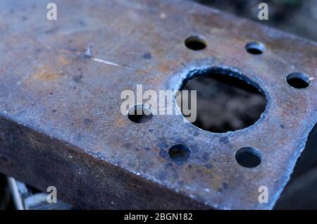 Gebohrte Löcher in den Metallkanal. Massives Metallteil mit sieben Strukturlöchern. Industrieller Hintergrund. Nahaufnahme. Selektiver Fokus. Stockfoto