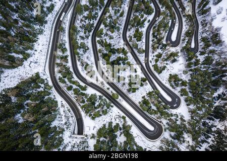 Luftaufnahme eines Autoschlangen auf einem Berg. Straße nach La Thuile Dorf und Skigebiet. Verschneite Bergserpentine im Aostatal in Italien. Stockfoto