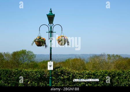 Hängende Körbe an Straßenlampe mit Nachbarschaftsüberwachung Schild und Blick über Medway Tal nach North Downs, Bidborough Ridge, Kent, England Stockfoto