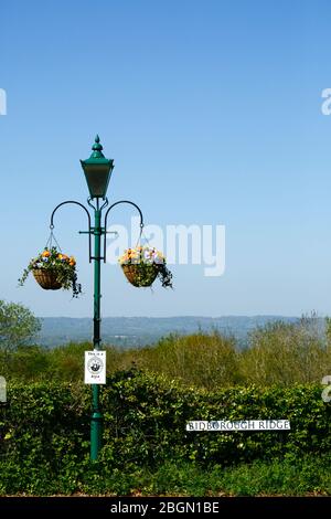 Hängende Körbe an Straßenlampe mit Nachbarschaftsüberwachung Schild und Blick über Medway Tal nach North Downs, Bidborough Ridge, Kent, England Stockfoto