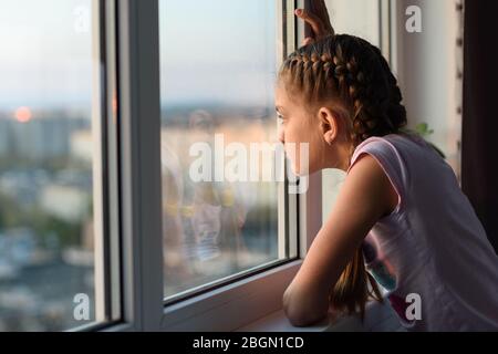 Mädchen gelangweilt zu Hause in Quarantäne schaut aus dem Fenster Stockfoto