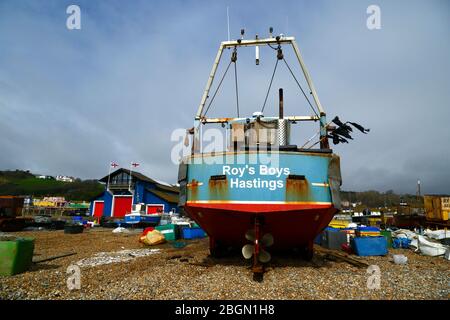 Roy's Boys Fischerboot am Stade Kiesstrand, Rettungsboot-Station im Hintergrund, Hastings, East Sussex, England, Großbritannien Stockfoto