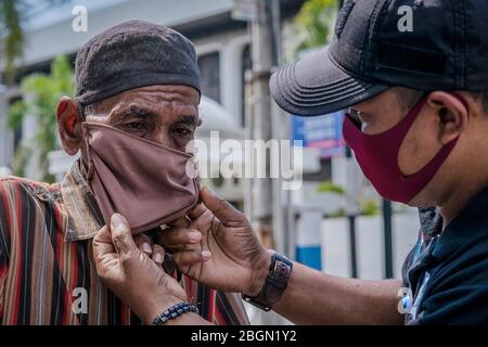 22. April 2020, Lhokseumawe, Aceh, Indonesien: Freiwillige Helfer der Anti-Betäubungsmittelbehörde LAN haben auf der Merdeka-Straße Masken auf den alten Mann gelegt, um die Ausbreitung des Coronavirus (COVID-19) in Lhokseumawe zu verhüten. Jüngste Berichte über COVID-19-Fälle, indonesische Beamte bestätigten 7.418 positive Fälle, 913 wurden mit 635 Toten erholt. (Bild: © Zikri Maulana/ZUMA Wire) Stockfoto