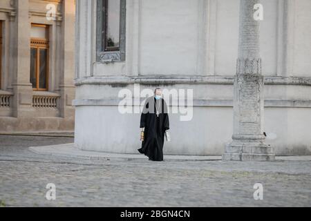 Bukarest, Rumänien - 18. April 2020: Ein orthodoxer christlicher Priester mit einer chirurgischen Maske wegen der COVID-19 Pandemie trägt das Heilige Licht während der Stockfoto