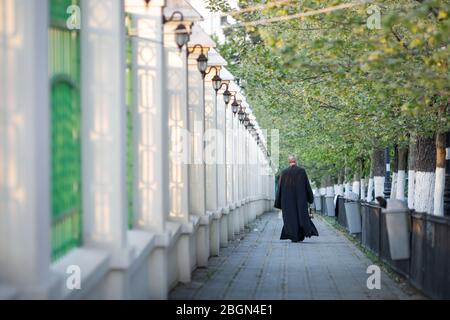 Bukarest, Rumänien - 18. April 2020: Ein orthodoxer christlicher Priester mit einer chirurgischen Maske wegen der COVID-19 Pandemie trägt das Heilige Licht während der Stockfoto