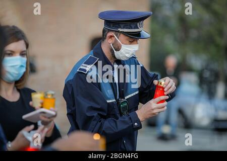 Bukarest, Rumänien - 18. April 2020: Rumänischer Polizist mit chirurgischer Maske wegen der COVID-19-Pandemie nimmt das Heilige Licht während der orthodoxen EAS Stockfoto