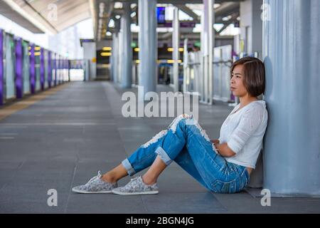 Asiatische Frauen sitzen auf dem Boden Hintergrund verschwommen Skytrain Station. Stockfoto