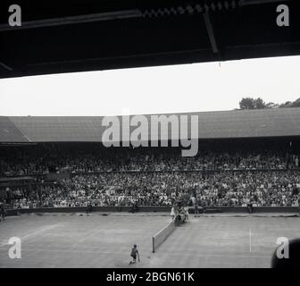 1950er Jahre, historisch, Wimbledon, Blick aus dieser Ära des Centre Court, voller Zuschauer, im berühmten Wimbledon Lawn Tennis Club, London, England, Großbritannien. Die Ursprünge des Tennisspiels in wimbledon gehen auf die Entscheidung des All England Croquet Club zurück, einen seiner Rasenflächen für den neuen Tennissport zu verwenden. was sich als populär erwies, dass der Verein seinen Namen änderte, um das Wort Tennis aufzunehmen und 1877 eine Meisterschaft auszutragen. Stockfoto