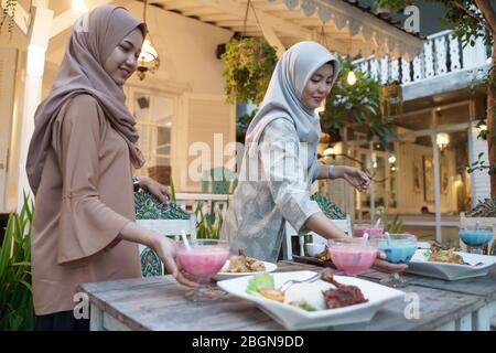 Schöne muslimische Frau bereitet den Tisch für das Fasten mit Freund und Familie am ramadan zu brechen Stockfoto