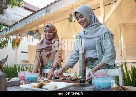 Schöne muslimische Frau bereitet den Tisch für das Fasten mit Freund und Familie am ramadan zu brechen Stockfoto