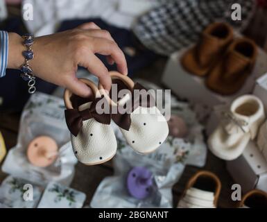 Schwangere Frau hält Babyschuhe für Neugeborene. Stockfoto